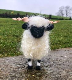 a stuffed sheep standing on top of a rock