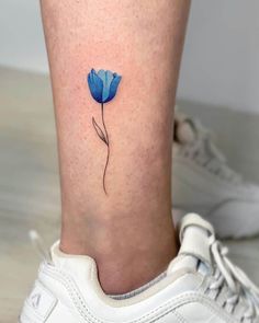 a small blue flower on the side of a woman's leg with her foot