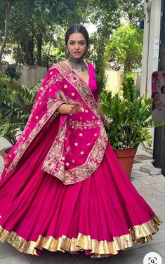 a woman in a pink lehenga with gold trimmings on the skirt