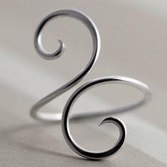 a close up of a silver ring on a white surface with the letter s in the middle