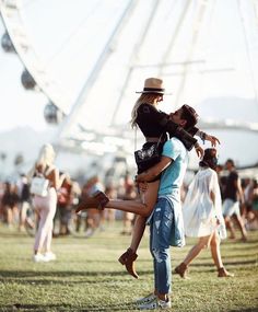 a man is holding a woman in his arms as they are dancing on the grass