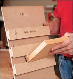 a man is holding a stack of unfinished pieces of wood with writing on the boards