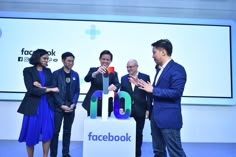 three men and two women standing in front of a facebook sign with the words facebook on it