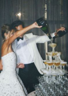 a bride and groom are standing in front of a cake with champagne being poured on it