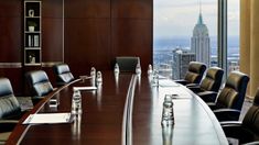 an empty conference table in front of a large window with cityscape behind it