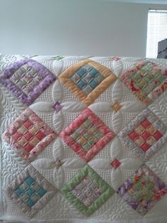 a white quilt with multicolored squares on it