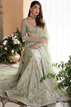 a beautiful woman in a green lehenga and matching with an elaborate necklace is posing for the camera