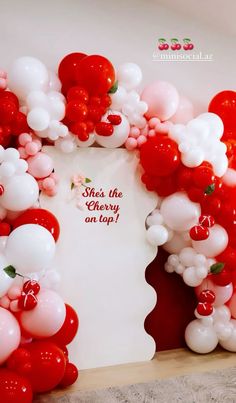 red and white balloons are arranged in the shape of a arch with a sign that says she's the cherry on top