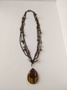 Beautiful vintage boho style necklace. Teardrop shaped tigers eye stone pendant with a filigree cutout copper-tone accent on top. The tigers eye has two small chips along the bottom but they're almost impossible to see. Strung on four antiqued bronze tone chains with pearl shell chips, crystal beads and copper colored faux pearls accents. Pendant measures 1.75 inches long. Necklace is 16 inches long with a lobster claw clasp and 3 inch adjustable chain. Shop Policies: Shipping: All items will be Bohemian Teardrop Pendant Copper Necklace, Bohemian Copper Teardrop Pendant Necklace, Brown Bohemian Teardrop Pendant Jewelry, Bohemian Brown Teardrop Pendant Jewelry, Tigers Eye Stone, Vintage Boho Style, Boho Style Necklaces, Vintage Boho Fashion, Teardrop Pendant