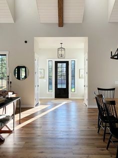 a large open floor plan with wood floors and white walls, black chairs and wooden table