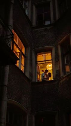 two people standing in an open window at night