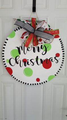 a merry christmas door hanger hanging on a white door with red, green and black polka dot ribbon