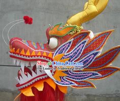 an elaborate dragon head with red hair and yellow feathers, on display in front of a gray wall