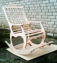 a white wooden rocking chair sitting in front of a brick wall