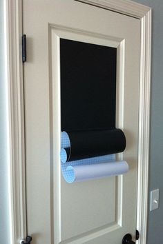 a black roll of toilet paper is hanging on the wall next to a white door