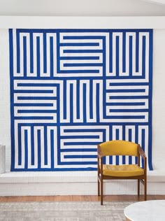 a yellow chair sitting in front of a blue and white wall with squares on it