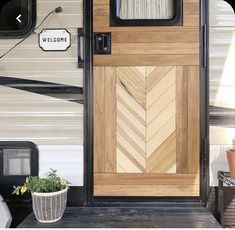 a wooden door with a welcome sign attached to it next to a potted plant