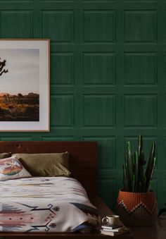 a bedroom with green painted walls and a bed in the foreground is a cactus plant