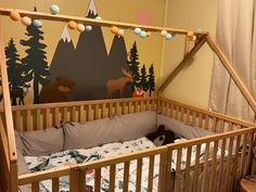 a baby crib with a mountain scene painted on the wall