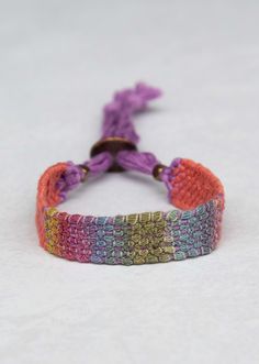 two bracelets that have different colors and designs on them, one with a knot at the end