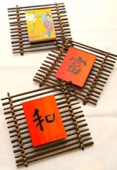 three pieces of art made out of bamboo sticks with chinese characters on them, sitting on a white surface