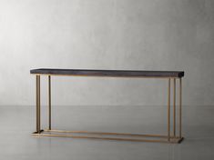 a black and gold console table with marble top on a concrete floor in front of a gray wall