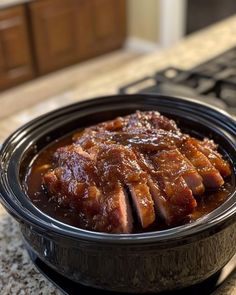 a black bowl filled with meat sitting on top of a counter next to a keyboard