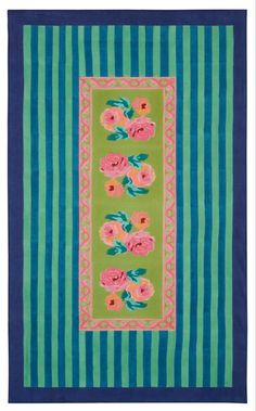 a blue and green rug with pink flowers on the border, in front of a striped background