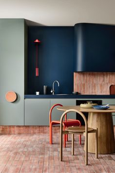 a kitchen with blue and green walls, wooden furniture and plants in the foreground