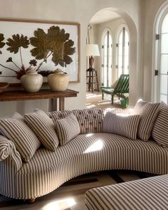 a living room filled with lots of furniture next to a wall mounted art piece on top of a wooden table