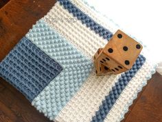 a wooden dice sitting on top of a blue and white knitted blanket next to a computer mouse