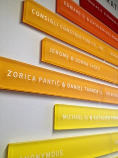 yellow and red name tags are hanging on the wall in front of a white wall