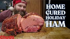 a man wearing a santa hat is looking at a large piece of meat