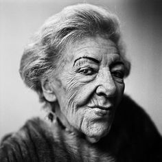 black and white photograph of an old woman with wrinkles on her face, looking at the camera