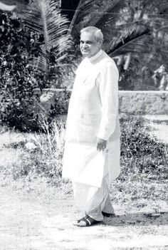 an old black and white photo of a woman standing in front of some bushes with her hands on her hips