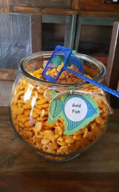 a glass jar filled with macaroni and cheese next to a sign that says gold fish