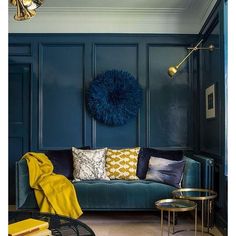 a living room with blue walls and gold accents on the couch, coffee table and lamp