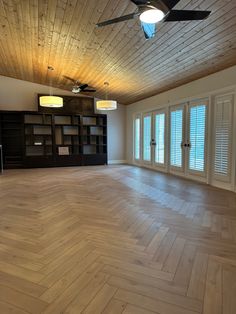 an empty room with wooden floors and ceiling fans