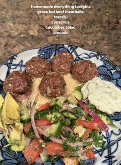 a blue and white plate topped with meatballs, veggies and sauces