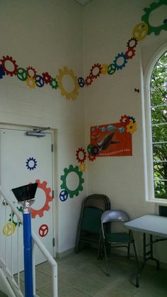 a room with several colorful gears painted on the wall and two chairs next to it