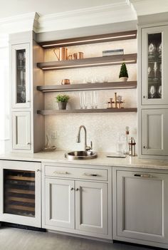 a kitchen with white cabinets and stainless steel sink, wine rack and built - in shelving