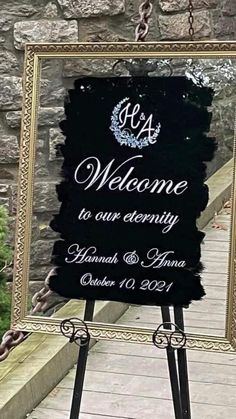 a welcome sign hanging from the side of a stone wall next to a chain link fence