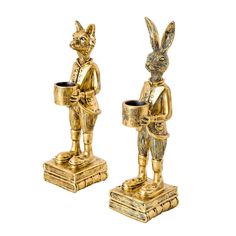 two gold colored figurines are standing next to each other, one is holding a cup