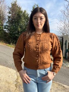 a woman standing in front of a road with her hands on her hips and looking at the camera