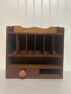 an old wooden desk with two drawers and one drawer on the bottom, in front of a white wall