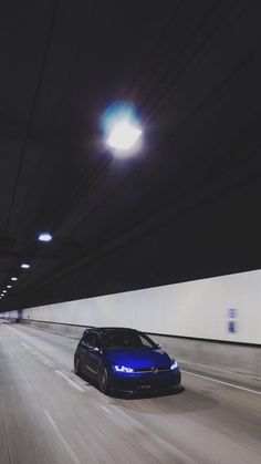 a blue car driving down a highway at night