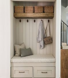 a white bench with drawers and baskets on it in a room that has wood paneling