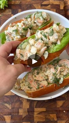 a person holding a piece of bread with crab salad on it and another hand reaching for the sandwich