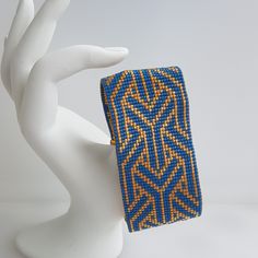 a blue and yellow beaded bracelet on a white mannequin headdress