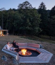 two people sitting in front of a fire pit